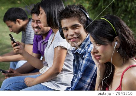 Young friends in lawn using cell phone Young friends in lawn using cell phone 7941510