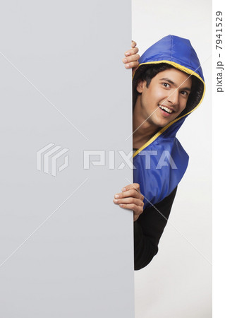 Young man hiding behind bill board 7941529