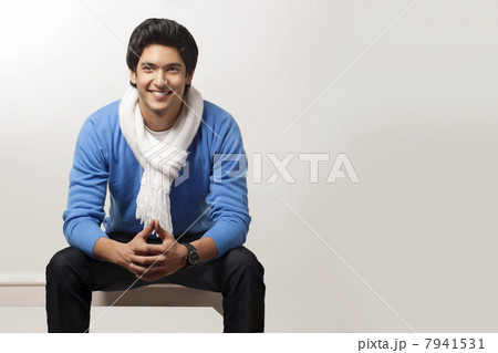 Smiling young man sitting over colored background 7941531