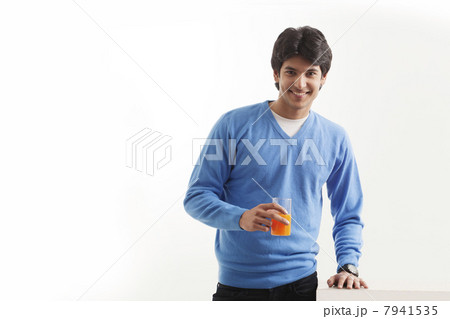 Portrait of young man holding glass of orange juice 7941535