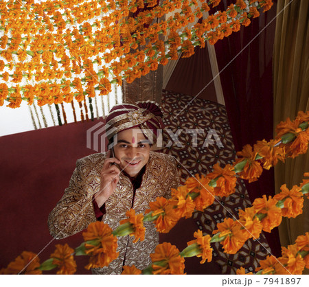 Young Indian bridegroom talking on mobile phone while looking up 7941897