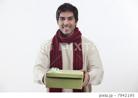 Portrait of young man holding gift box over white background Portrait of young man holding gift box over white background 7942195