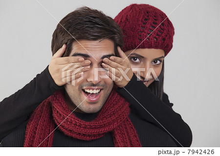 Young woman covering mans eyes Young woman covering mans eyes 7942426