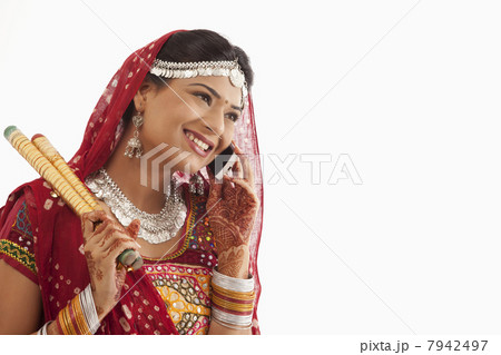 Female dandiya dancer talking on a mobile phone Female dandiya dancer talking on a mobile phone 7942497