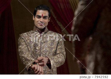 Mirror reflection of young bridegroom getting into ceremonial outfit 7942592
