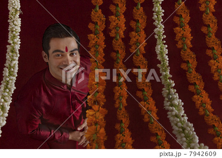 Portrait of smiling young bridegroom behind wreath 7942609