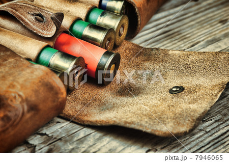 Old hunting cartridges and bandoleer on a wooden table 7946065