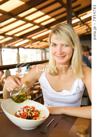 Beautiful young woman eating healthy vegetable salad in a restau 7954783
