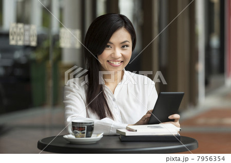 Chinese business woman using a tablet computer in a cafe. 7956354