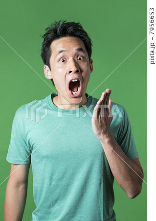 Surprised Chinese man standing against green background. 7956653