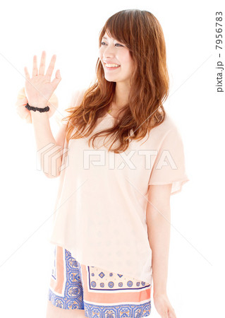 楽しそうな笑顔で友達に手を振る爽やかな夏服を着た代の女の子の写真素材