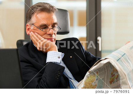 Boss in his office reading newspaper 7976091