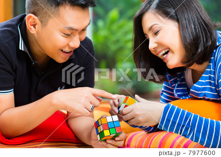 Asian couple at home playing with magic cube Asian couple at home playing with magic cube 7977600