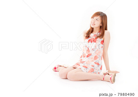後ろに手をついて座る花柄の可愛いワンピースを着た代の女の子の写真素材