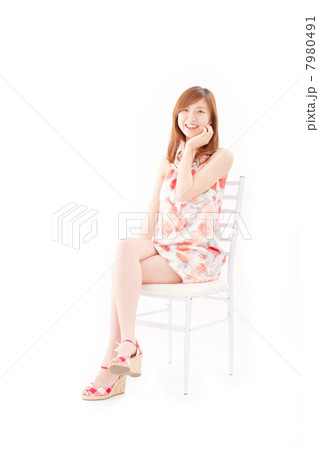 真っ白な椅子に座って頬に手を添えて笑う20代の綺麗な女の子 7980491