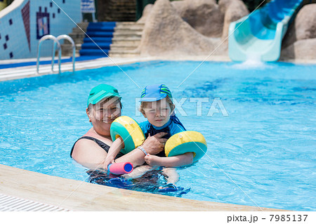 Grandmother and grandson swimming together in the pool 7985137