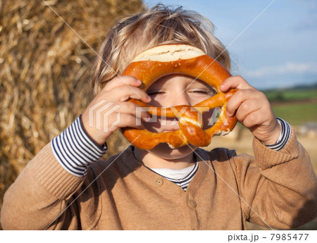 Lovely little boy of two years with pretzel on hay field 7985477