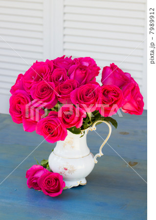Mauve roses in vase on blue table 7989912