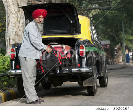 Sikh taxi driver loading luggage into the dickie 8026164