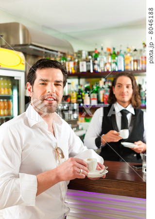 Barista with client in his cafe or coffeeshop Barista with client in his cafe or coffeeshop 8046188