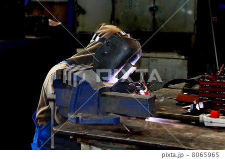 Welder working in production workshop on a workbench 8065965