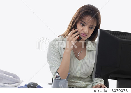 Angry female executive on call while using computer Angry female executive on call while using computer 8070078