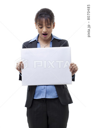 Portrait of surprised young businesswoman holding blank card over white background 8070485