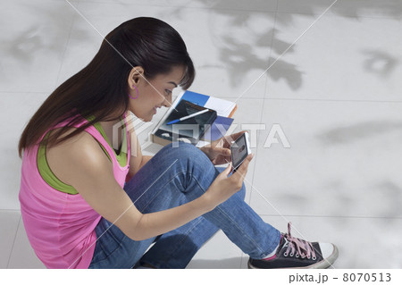 High angle view of happy female college student using cell phone High angle view of happy female college student using cell phone 8070513