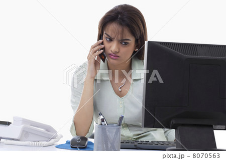 Angry businesswoman on call while using computer 8070563