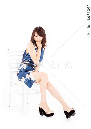 爽やかなワンピースを着て椅子に座ってポーズをとるアラサーの女の子の写真素材