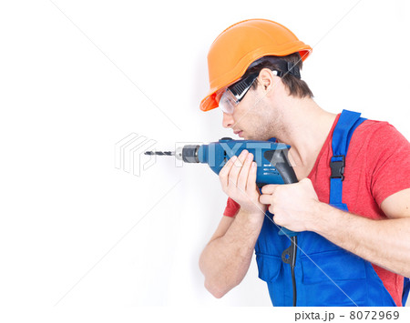 A man drilling a hole in the wall. 8072969