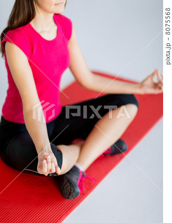 girl sitting in lotus position and meditating 8075568