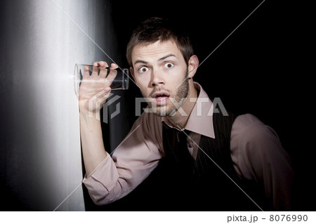 Handsome young man using glass to eavesdrop 8076990