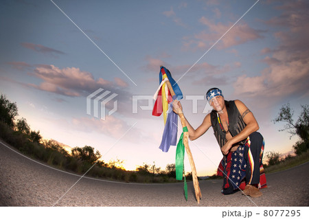 Indigenous man in the middle of a road with ceremonial pole and 8077295