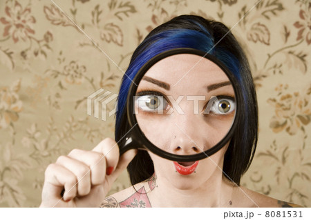Pretty Woman with a Magnifying Glass in front of her Face 8081531