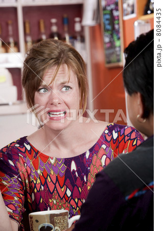 Appalled woman in coffee house with male friend Appalled woman in coffee house with male friend 8084435