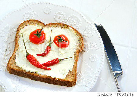 Food arranged into a smiley face on sandwich 8098845