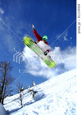 Snowboarder jumping against blue sky 8114668