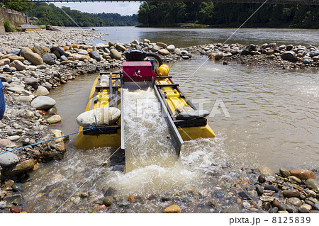 Suction dredge mining alluvial gold on an Amazonian riverbank in Ecuador 8125839
