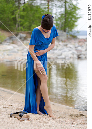 Beautiful girl in a blue dress stockings strips on the lake 8152970