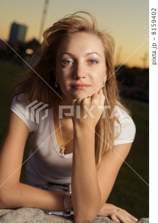 half-length portrait of 20s blond caucasian young pretty woman in sunset lightning looking at camera 8159402