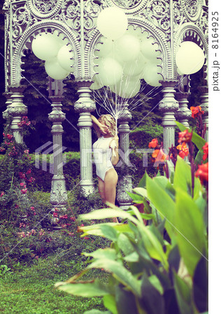 Sentiment. Beautiful Relaxed Blonde holding Air Balloons in the Garden 8164925