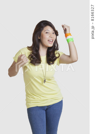 Portrait of happy young woman in casuals wearing Indian tricolor bangles over white background 8166327