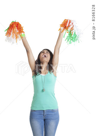 Young woman in casual wear holding up tricolor pom poms over white background 8166328
