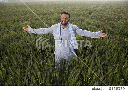 Portrait of an Indian man standing with arms out in a field Portrait of an Indian man standing with arms out in a field 8166329