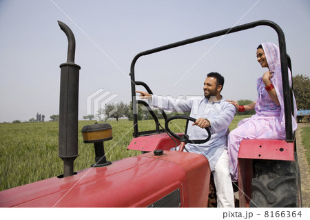Indian couple on tractor with man pointing at something Indian couple on tractor with man pointing at something 8166364