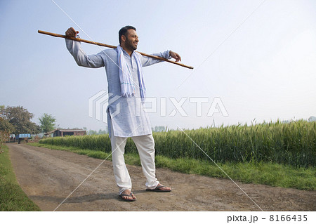 Full length of an Indian man standing with a stick across his shoulders Full length of an Indian man standing with a stick across his shoulders 8166435