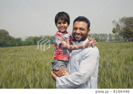 Portrait of a happy man carrying his son with wheat field in background Portrait of a happy man carrying his son with wheat field in background 8166496