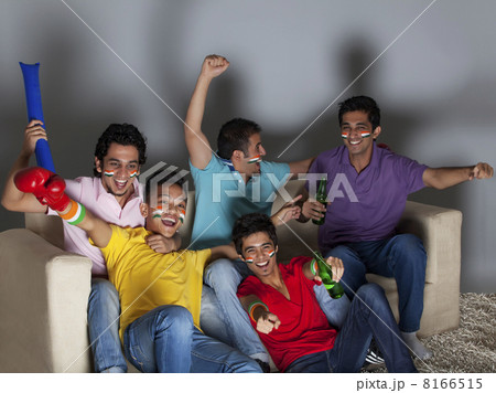 Cheerful young male friends enjoying a boxing match together at home 8166515