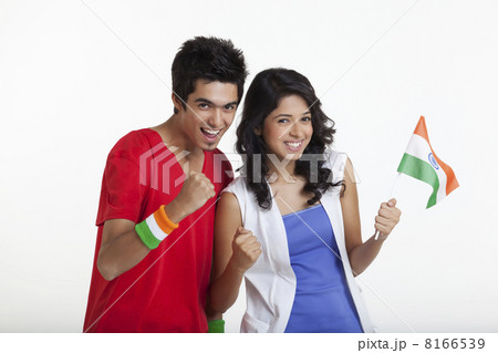 Portrait of happy young boy cheering with female friend holding Indian flag over white background 8166539
